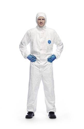 Eine Person in einem weißen Schutzanzug mit blauen Handschuhen, die mit leicht geöffneten Armen steht und die volle Länge des Anzugs präsentiert.