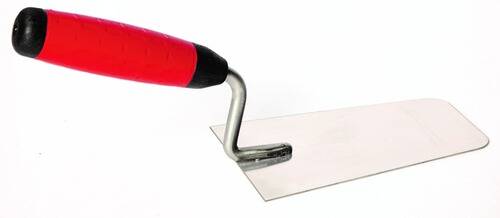 Eine Kelle mit rotem Griff und Metallklinge ist auf einer ebenen Fläche positioniert, wahrscheinlich zum Verteilen oder Glätten von Material.