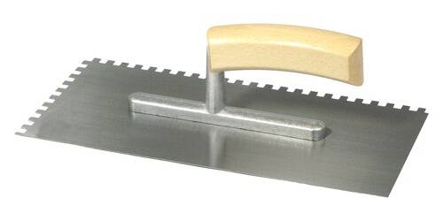 Eine Nahaufnahme einer gezahnten Kelle mit Holzgriff, die zum Auftragen von Klebstoff auf Oberflächen bei Fliesen- oder Bodenarbeiten verwendet wird.