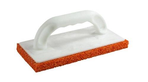 Ein Reinigungsschwamm mit weißem Griff und einer strukturierten orangefarbenen Schrubberoberfläche, der zum Reinigen oder Schrubben verwendet wird.