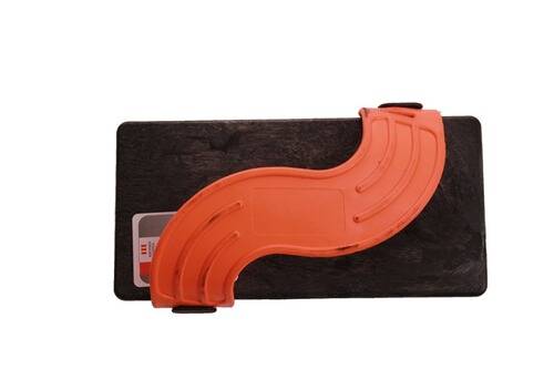 Ein orangefarbener halbkreisförmiger Kunststoffschutz ist an einem kleinen rechteckigen schwarzen Brett angebracht, möglicherweise Teil einer Schutzabdeckung oder eines Werkzeugzubehörs.