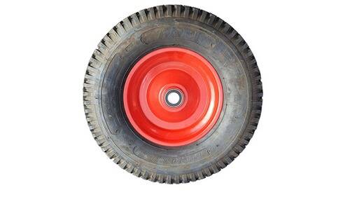 Ein schwarzer Gummireifen mit einer roten Metallradkappe, geeignet für kleine Fahrzeuge oder Karren. Das Reifenprofil ist sichtbar und weist auf Langlebigkeit hin.