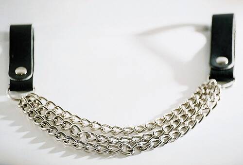 Eine Nahaufnahme einer silbernen Kettenkette mit mehreren Strängen, die sanfte Schatten vor einem weißen Hintergrund wirft.