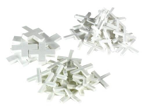 Weiße Fliesenabstandhalter in zwei kleine und einen großen Haufen angeordnet.