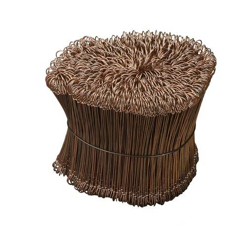 Ein Hocker aus verflochtenen metallischen Drähten, der eine strukturierte, geschleifte Oberfläche auf der Oberseite und an den Seiten bildet, in glänzender Kupferfarbe.