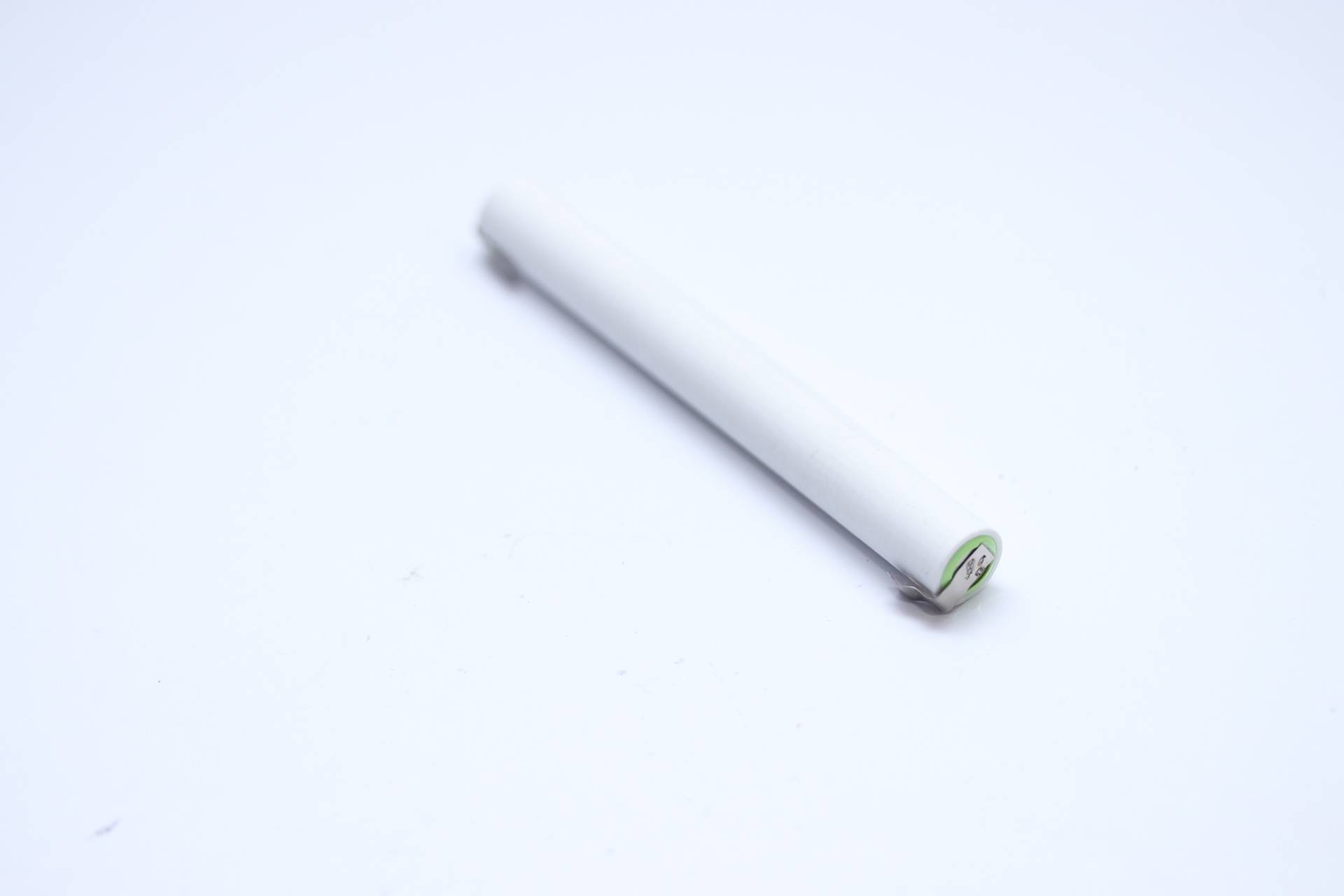 Eine Nahaufnahme eines einzelnen weißen Zylinders, der einem Stift oder Stylus ähnelt, auf einer weißen Oberfläche platziert mit einem minimalen Schatten auf einer Seite.