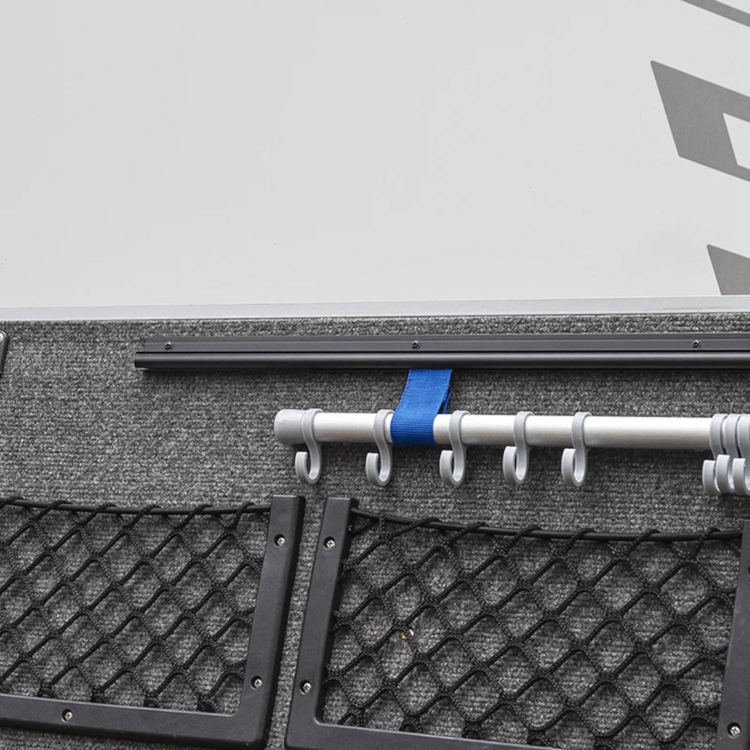 Reihe von Angelruttenhaltern auf der Reling eines Bootes mit mehreren befestigten Ruten. Metallstangen und blaue Gurte sind sichtbar.