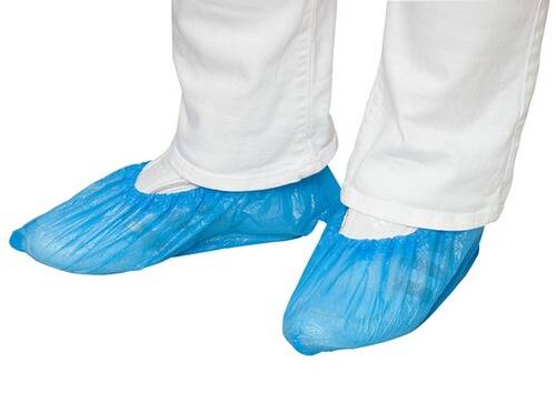 Person in weißer Hose und blauen Einweg-Schuhüberzügen, geeignet zur Aufrechterhaltung der Sauberkeit in kontrollierten Umgebungen.