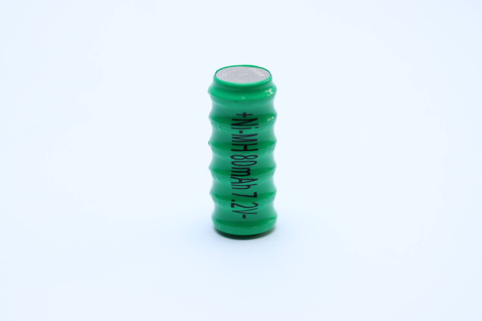 Eine grüne zylindrische Batterie, die aufrecht steht, mit sichtbaren Markierungen, die 