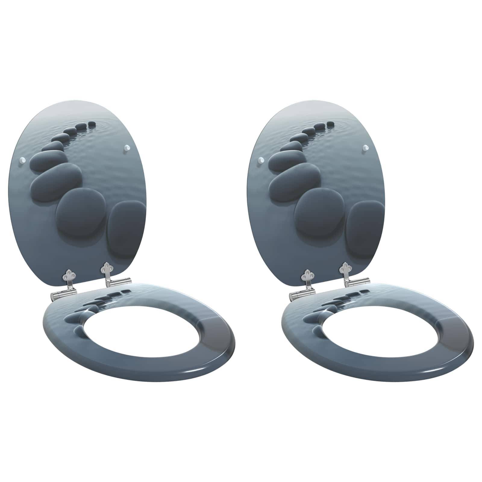 Zwei gespiegelte graue Toilettensitze mit Deckeln, die ein ruhiges Bild von Steinen auf einer glatten Oberfläche zeigen.