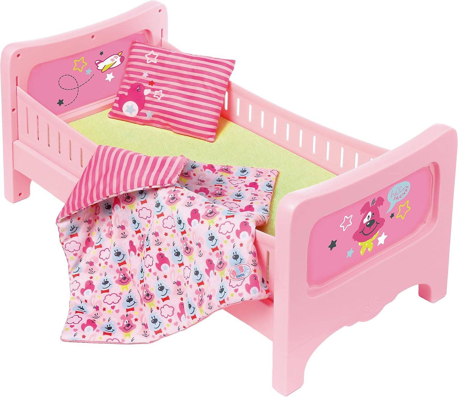 Ein kleines rosa Spielzeugbett mit einer grünen Matratze, einem gestreiften Kissen und einer bunten Decke mit Cartoon-Tiermotiven und Sternen.