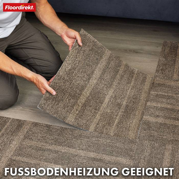 Eine Person legt ein quadratisches Stück brauner Teppichfliese auf einen Boden. Der Text lautet „FUSSBODENHEIZUNG GEEIGNET