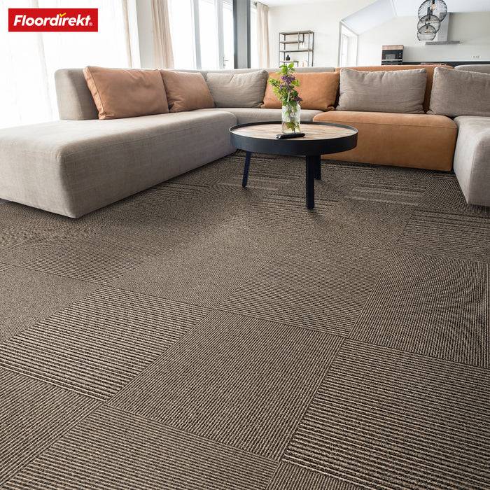 Modernes Wohnzimmer mit einem großen grauen Ecksofa, rundem schwarzem Couchtisch und gemusterten Teppichfliesen auf dem Boden.