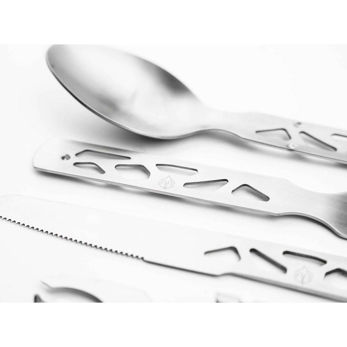 Nahaufnahme eines eleganten, modernen Bestecksatzes aus Metall mit Löffel und Messer mit Sägeschliff sowie geometrischen Designs vor weißem Hintergrund.