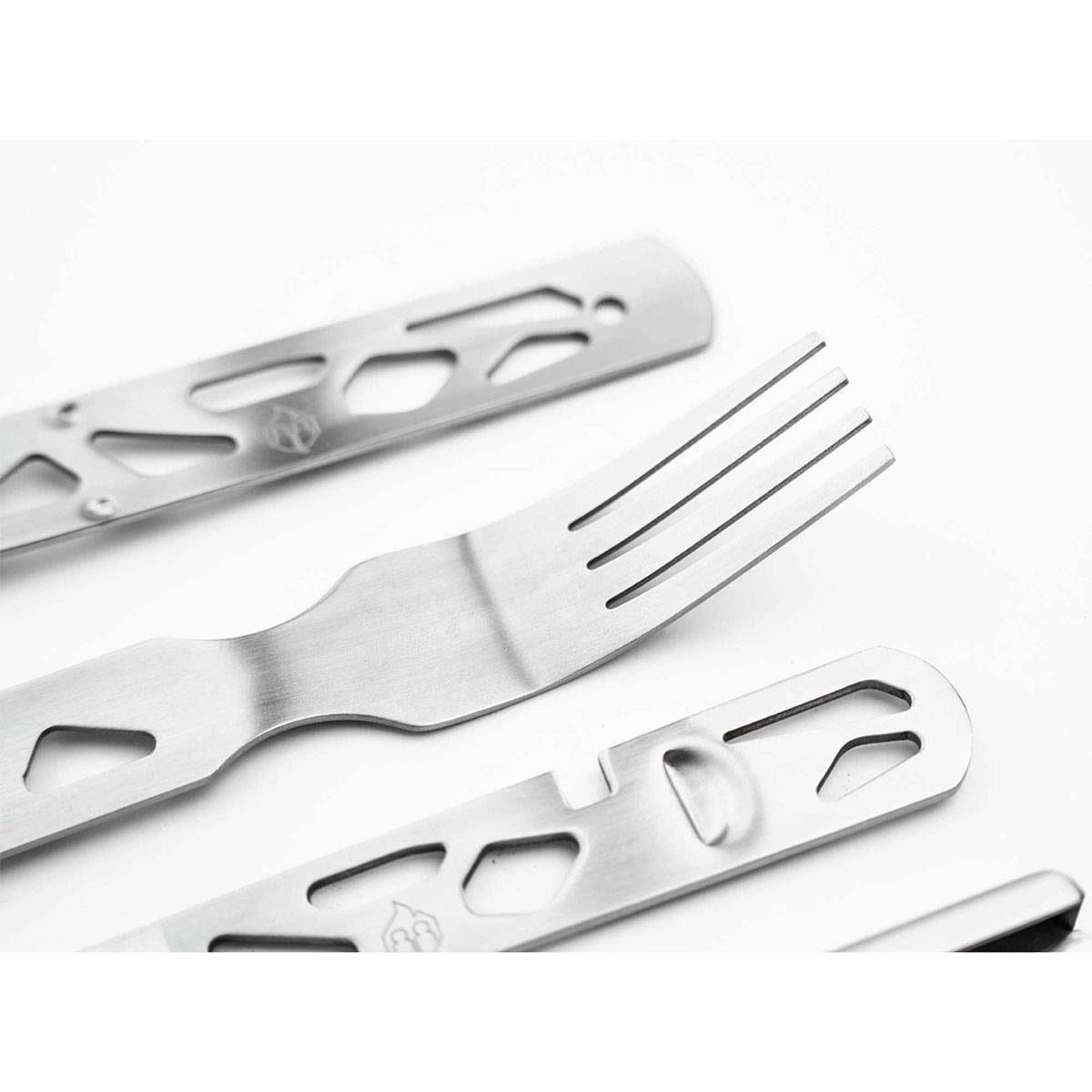 Eine Nahaufnahme von Edelstahlgabeln mit modernen, geometrischen Ausschnitten an den Griffen, diagonal auf weißem Hintergrund angeordnet.