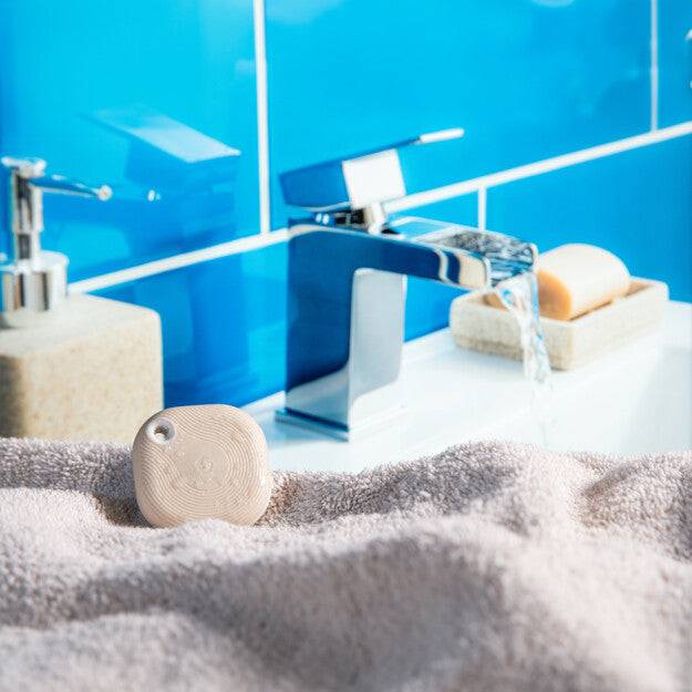 Ein Badezimmerbecken mit glänzendem blauem Fliesenhintergrund, einem modernen Chromwasserhahn, einem Seifenspender und einem Stück Seife auf der rechten Seite.