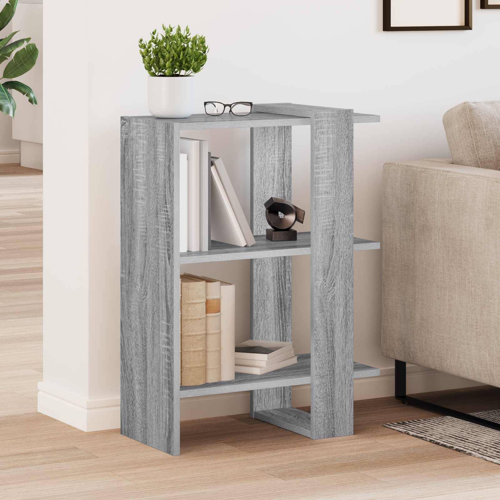 Grauer Holz-Beistelltisch oder kleines Bücherregal neben einem beigen Sofa, oben mit Büchern, Brillen und einer Topfpflanze.