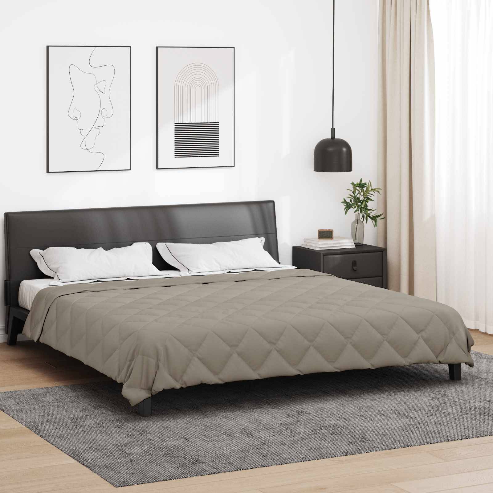 Ein modernes Schlafzimmer mit einem grauen Bett, schwarzem Kopfteil und weißen Kissen. Zwei gerahmte Kunstwerke an der Wand und natürliches Licht von einem Fenster.