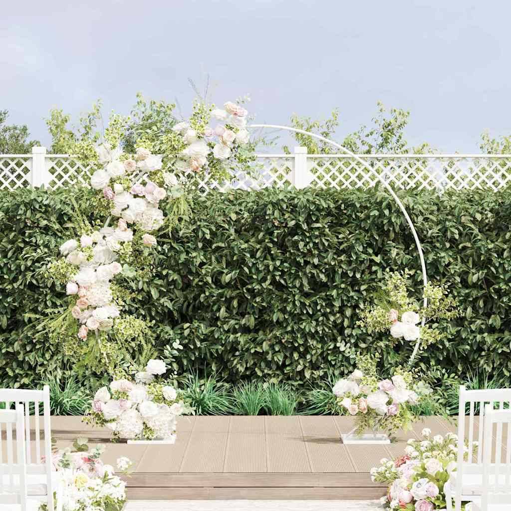 Ein blumenbogenschmuck mit rosa und weißen Blüten steht auf einer hölzernen Plattform, umgeben von Grünpflanzen und weißen Stühlen.