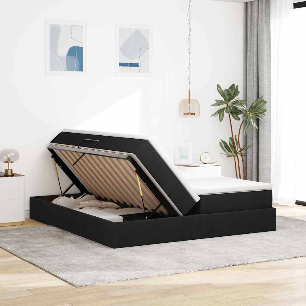 Modernes Schlafzimmer mit schwarzem Speicherbettgestell, das angehoben ist und den Stauraum darunter zeigt. Die minimalistische Einrichtung umfasst Wandkunst, eine Pendelleuchte, eine Pflanze und einen Teppich.
