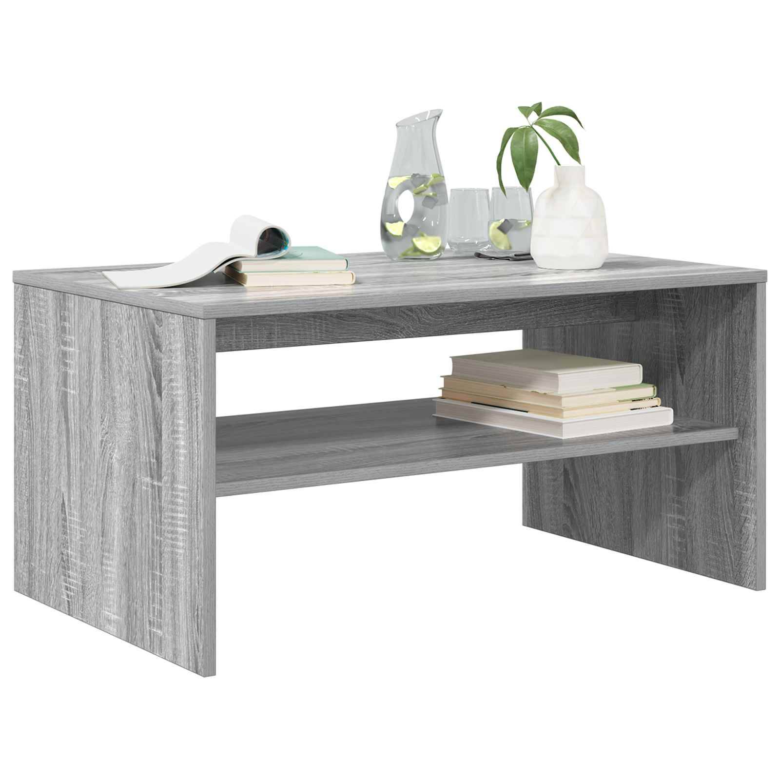 Ein grauer Holz-Couchtisch mit offenem Regal, auf dem Bücher, ein Glaskrug mit Zitronenscheiben und eine kleine Topfpflanze stehen.