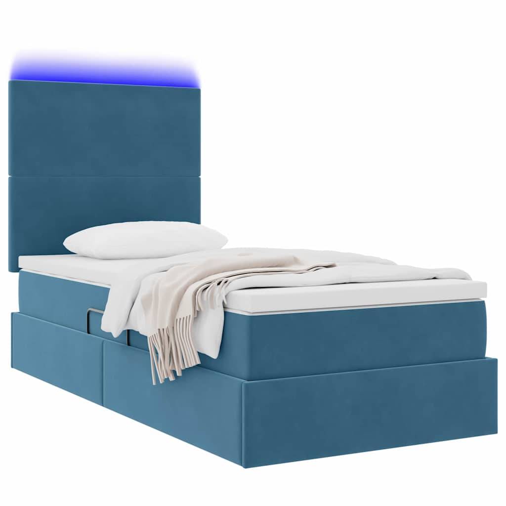 Ein blau gepolstertes Bett mit integrierten Schubladen zur Aufbewahrung, ein Kopfteil mit stimmungsvoller blauer Beleuchtung sowie ein weißes Kissen und eine weiße Decke.