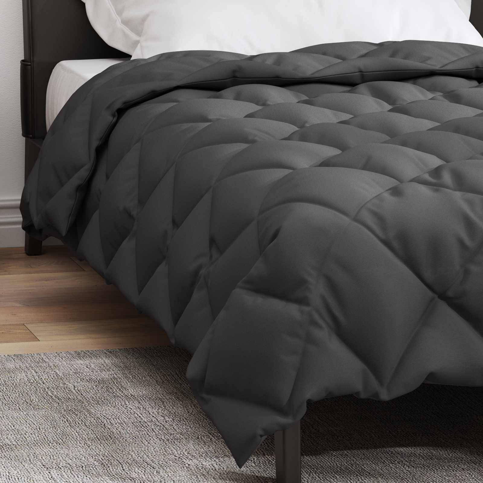 Ein ordentlich gemachtes Bett mit einer dunkelgrauen, gesteppten Steppdecke, weißen Kissen und einem Holzboden.