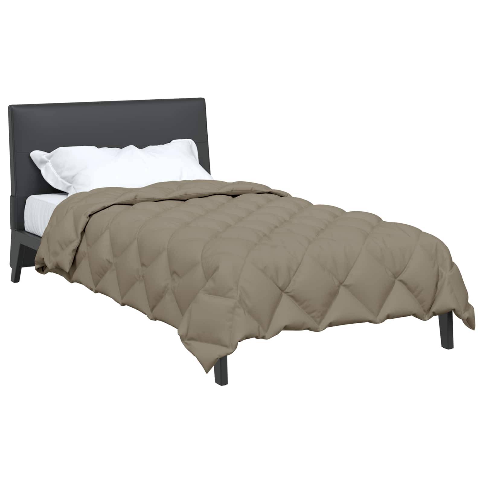 Ein ordentlich gemachtes Bett mit grauem gepolstertem Kopfteil, weißem Kissen und einer taupefarbenen gesteppten Tagesdecke.