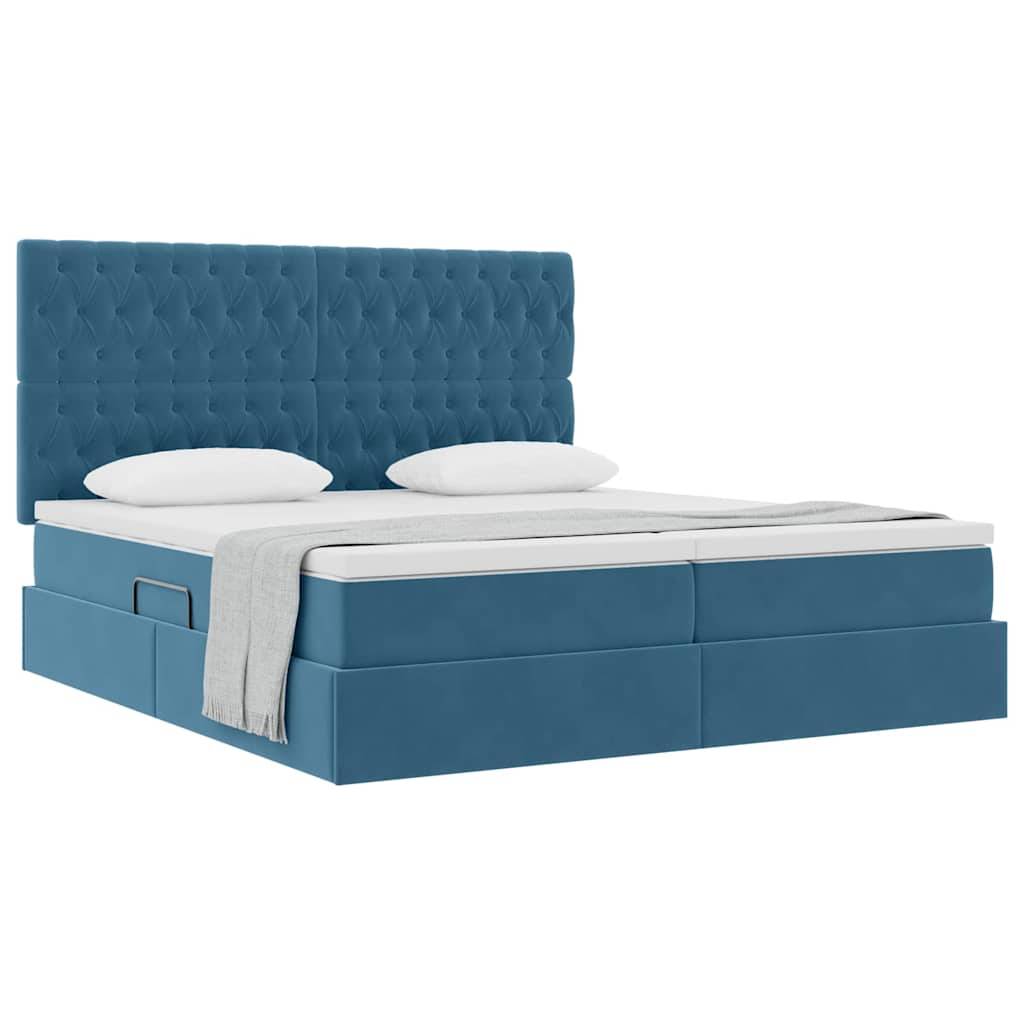 Ein blaugepolstertes Bett mit gestepptem Kopfteil, zwei weißen Kissen und einer zusammengefalteten grauen Wurfdecke auf der Seite.