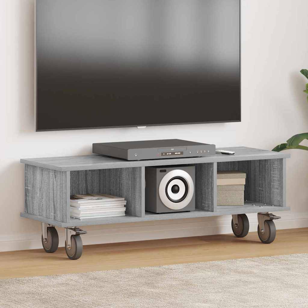 Eine graue Holzmedienkommode auf Rollen, die Bücher, einen Lautsprecher und ein elektronisches Gerät hält, positioniert unter einem wandmontierten Fernseher.