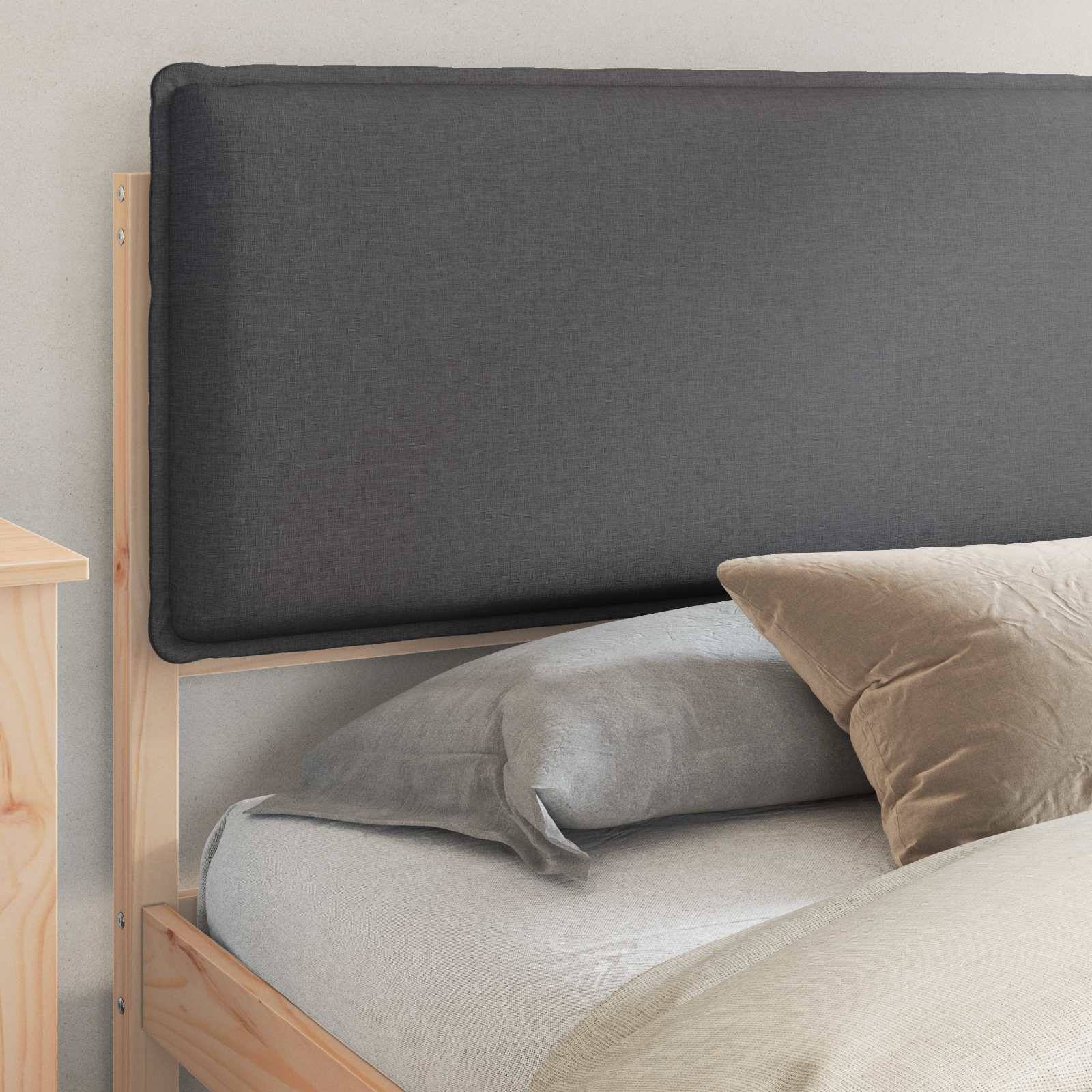 Ein ordentlich gemachtes Bett mit einem grauen Kopfkissen und einem beigefarbenen Kopfkissen, vor einem Holzrahmen und einem grau gepolsterten Kopfteil in einem minimalistischen Schlafzimmer.