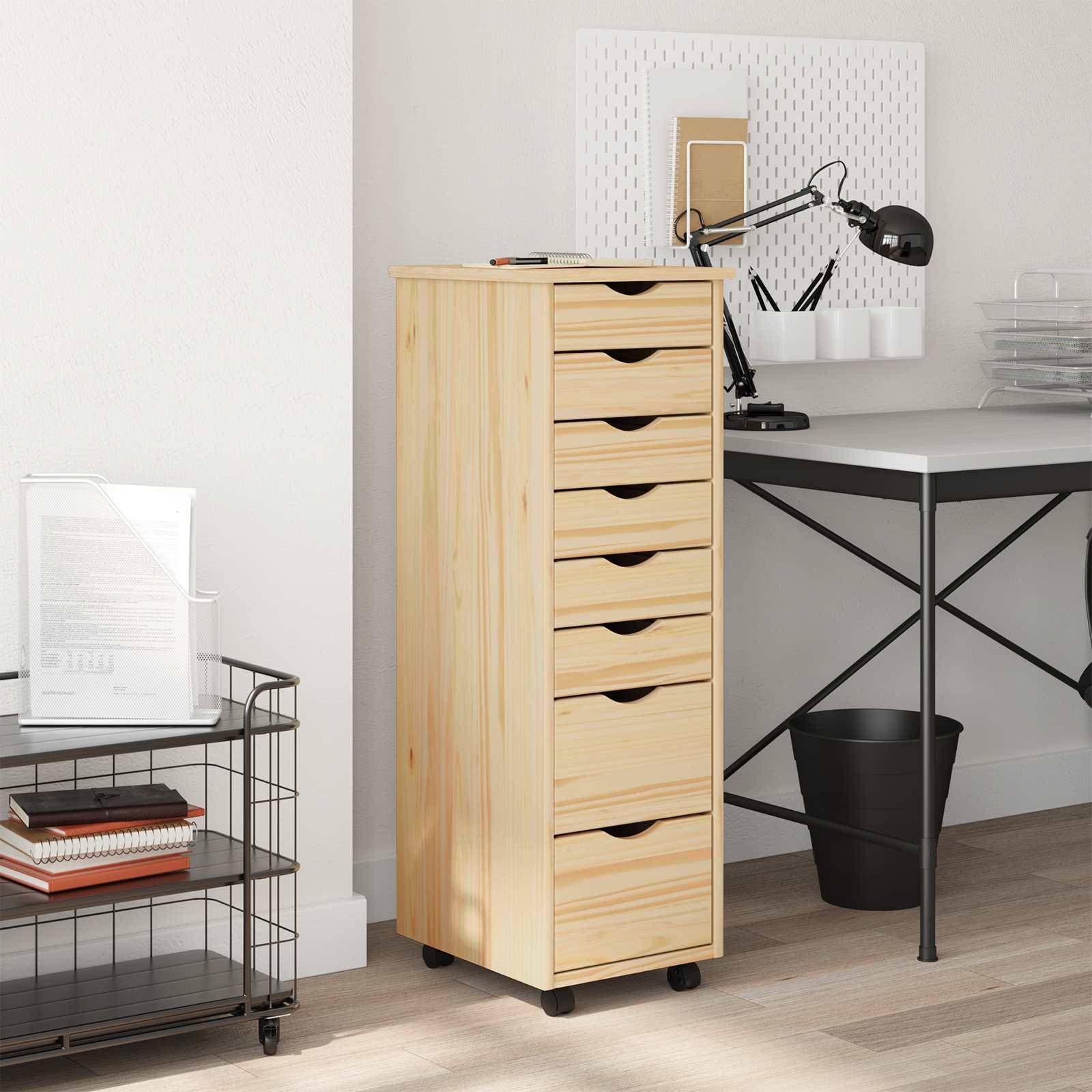 Ein kleines Homeoffice-Setup mit einer Schubladeneinheit aus hellem Holz, einem schwarzen Metallschreibtisch, einem schwarzen Stuhl und einer angebrachten verstellbaren Lampe.