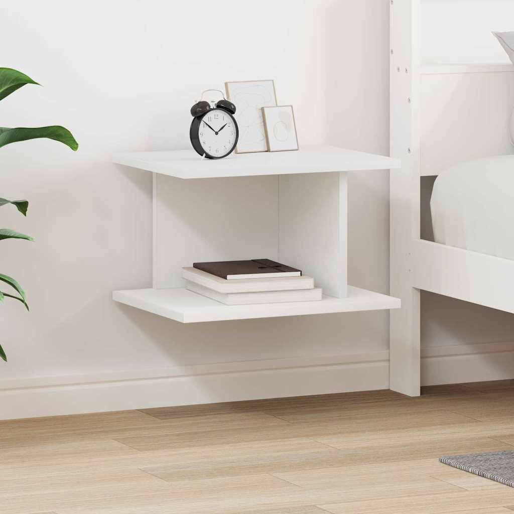 Ein weißes Eckschwebegal neben einem Bett hält einen schwarzen Wecker, eine kleine Topfpflanze und gestapelte Bücher in einem minimalistischen Schlafzimmer.