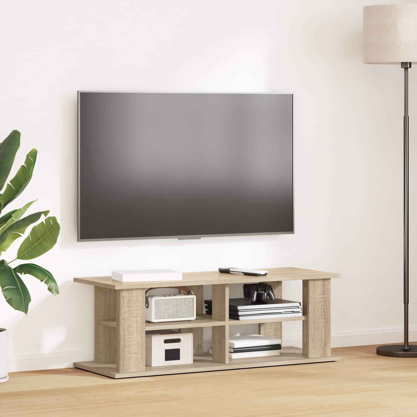Ein modernes Wohnzimmer mit einem an der Wand montierten Fernseher über einem Holzständer, auf dem Dekorationen und Geräte stehen. Eine Zimmerpflanze und eine Stehleuchte flankieren die Anordnung.