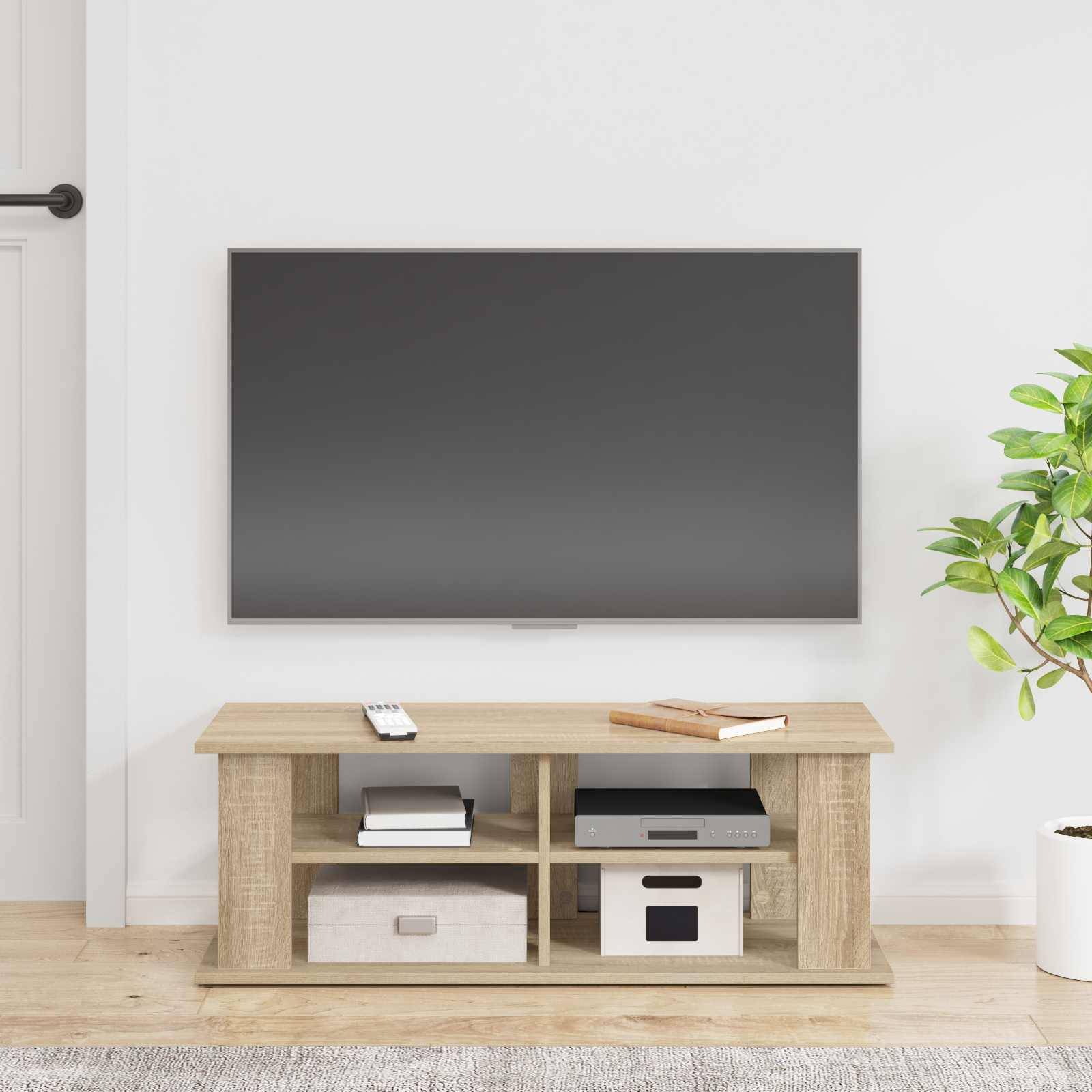 Ein modernes Wohnzimmer mit einem Flachbildfernseher, der an einer weißen Wand über einem hellen Holz-Fernsehschrank angebracht ist, auf dem Elektronik und Dekorationsgegenstände stehen.