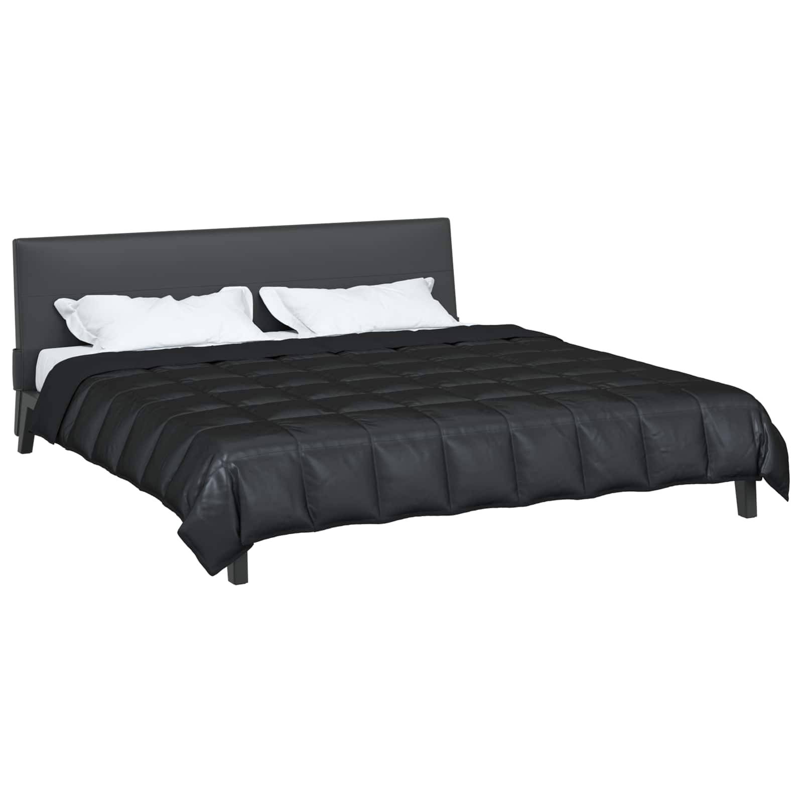 Ein modernes Bett mit dunklem grauem Rahmen, schwarzer gesteppter Tagesdecke und zwei weißen Kissen, das einen minimalistischen Schlafzimmerstil andeutet.