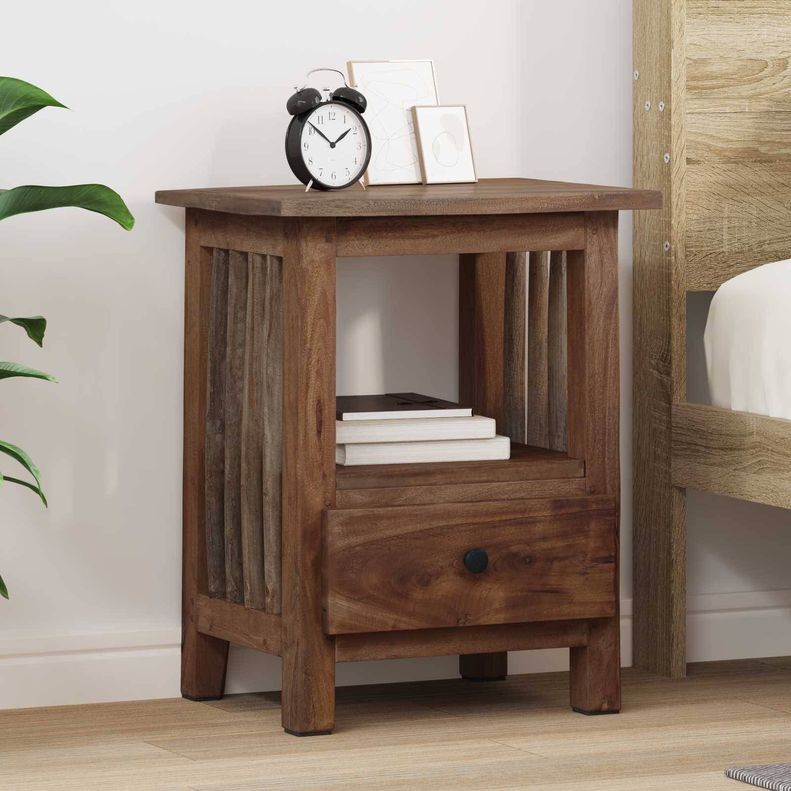 Ein Holznachttisch mit einer Schublade, auf dem ein schwarzer Wecker, ein kleiner Rahmen und Bücher stehen, steht neben einem Bett in einem einfachen Zimmer.