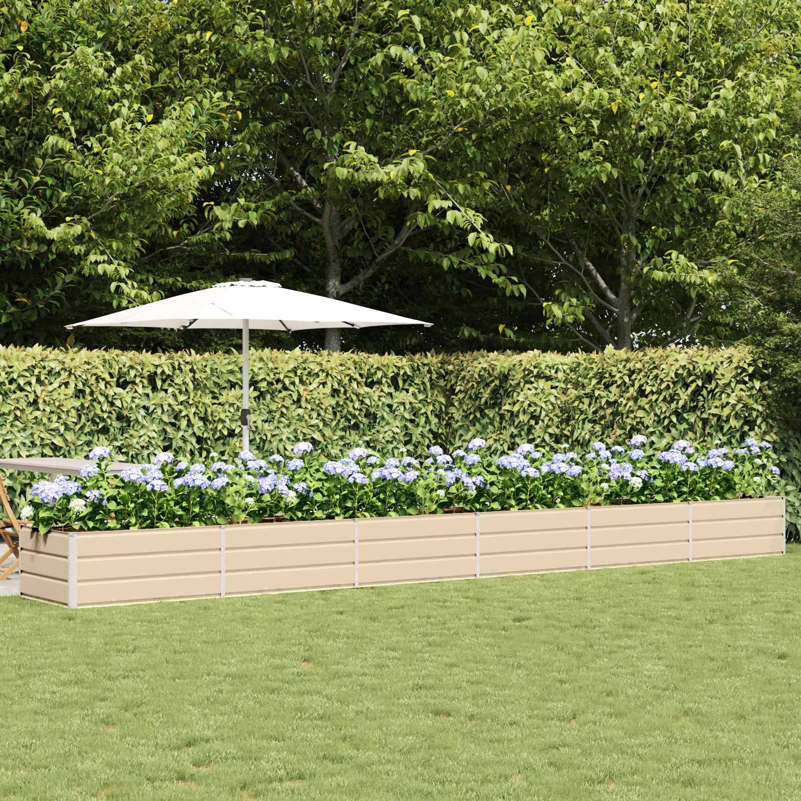 Ein langer beige Blumenkasten, gefüllt mit violetten und weißen Blumen, steht auf einer Grünfläche. Dahinter befinden sich ein weißer Regenschirm und üppig grüne Bäume.