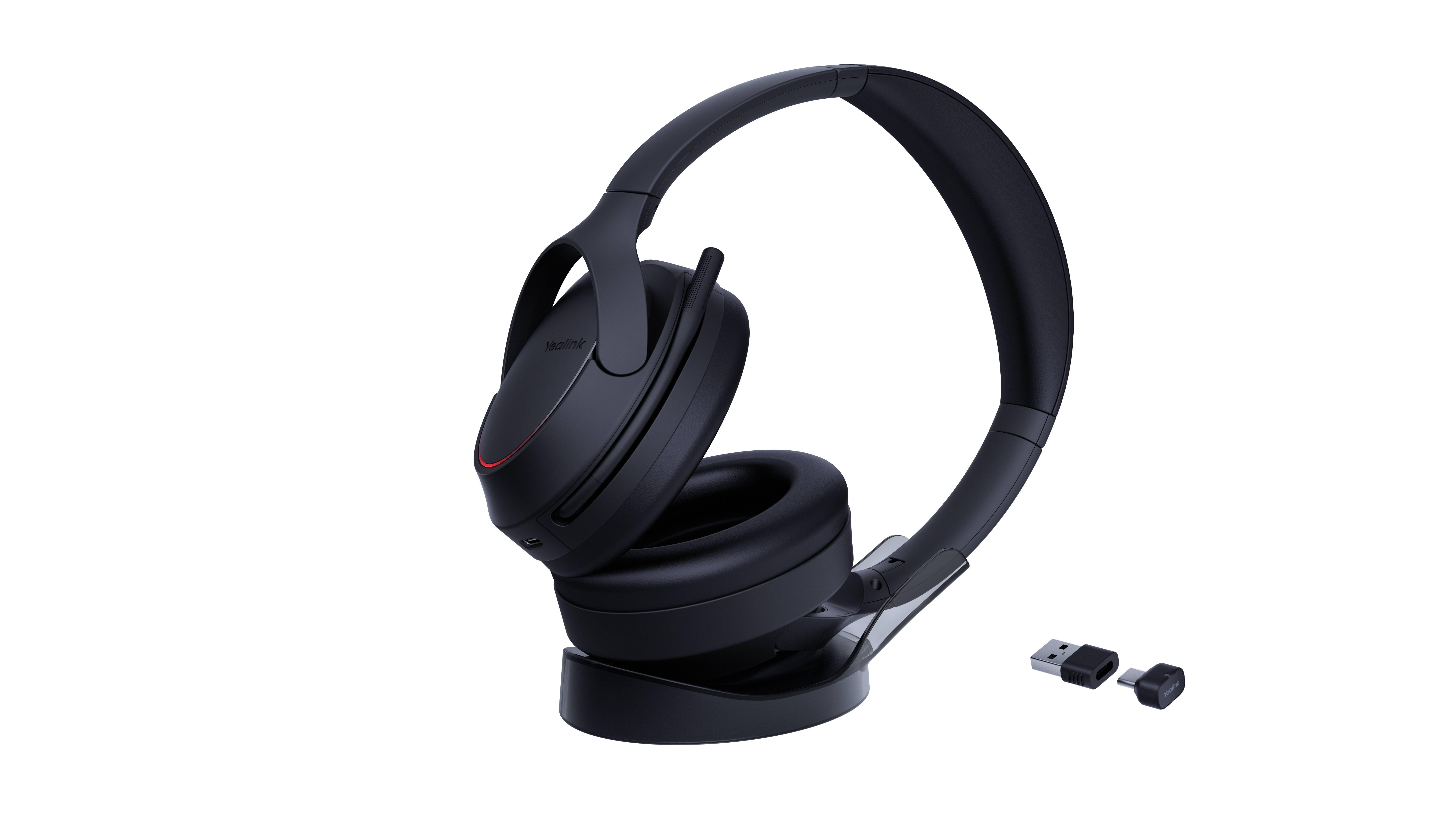 Schwarze Over-Ear-Kopfhörer mit Ladestation und USB-Adapter auf schwarzem Hintergrund