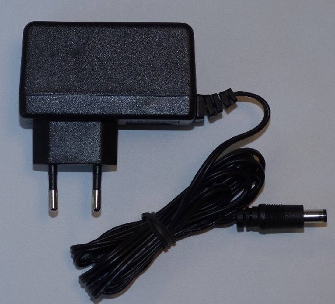 Ein schwarzer Stromadapter mit europäischem Stecker und einem aufgewickelten Kabel mit Hohlstecker.