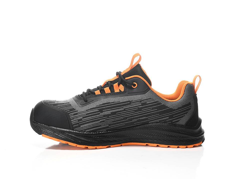 Ein schwarzer und grauer Sportschuh mit orangefarbenen Akzenten und Sohle, von der Seite auf weißem Hintergrund gezeigt.