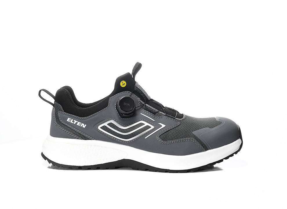 Seitenansicht eines grauen Sportschuhs mit weißer Sohle und einem einzigartigen Befestigungssystem. Der Schuh zeigt den Markennamen „Elten