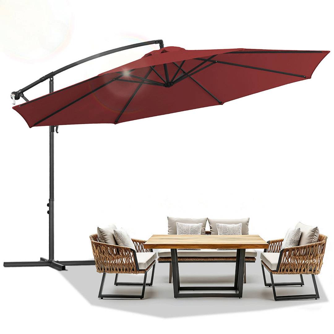 Gartenmöbelset im Freien mit einem Holztisch, vier Korbstühlen mit Kissen und einem großen roten Freiarmschirm darüber.
