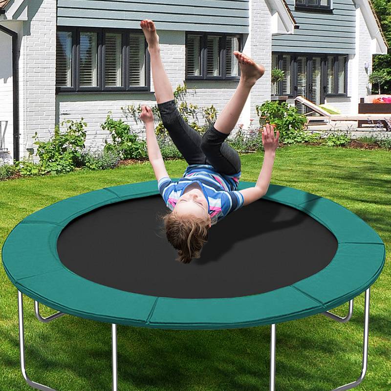 Kind in Bewegung, das ein gestreiftes Hemd trägt, springt freudig auf einem grünen Trampolin im Hinterhof, mit einem modernen Haus im Hintergrund.