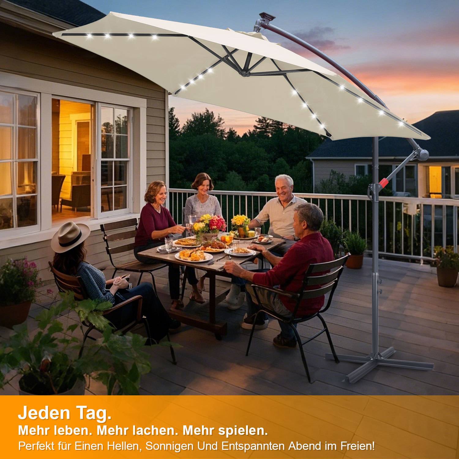 Vier Personen sitzen um einen Tisch auf einer Terrasse und teilen sich eine Mahlzeit unter einem großen Schirm mit Lichtern. Die Bildunterschrift lautet: „Jeden Tag. Mehr leben. Mehr lachen. Mehr spielen.