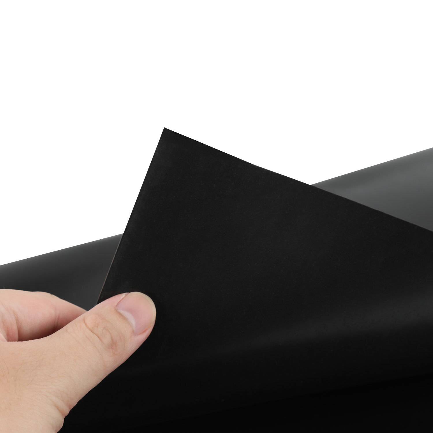 Eine Hand, die ein schwarzes Blatt Papier gegen einen weißen Hintergrund hält und die Dicke und Textur des Papiers demonstriert.