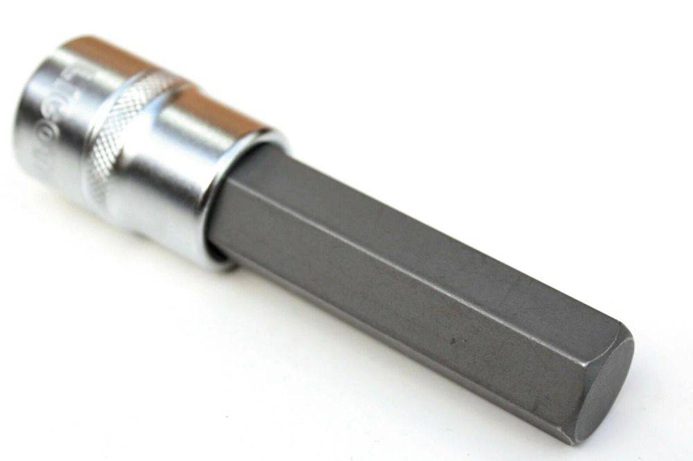 Eine Nahaufnahme eines metallischen Werkzeugs mit einem silbernen Griff und einem rechteckigen Schaft, möglicherweise ein Bohrer oder Schraubendreher. Der Hintergrund ist weiß.