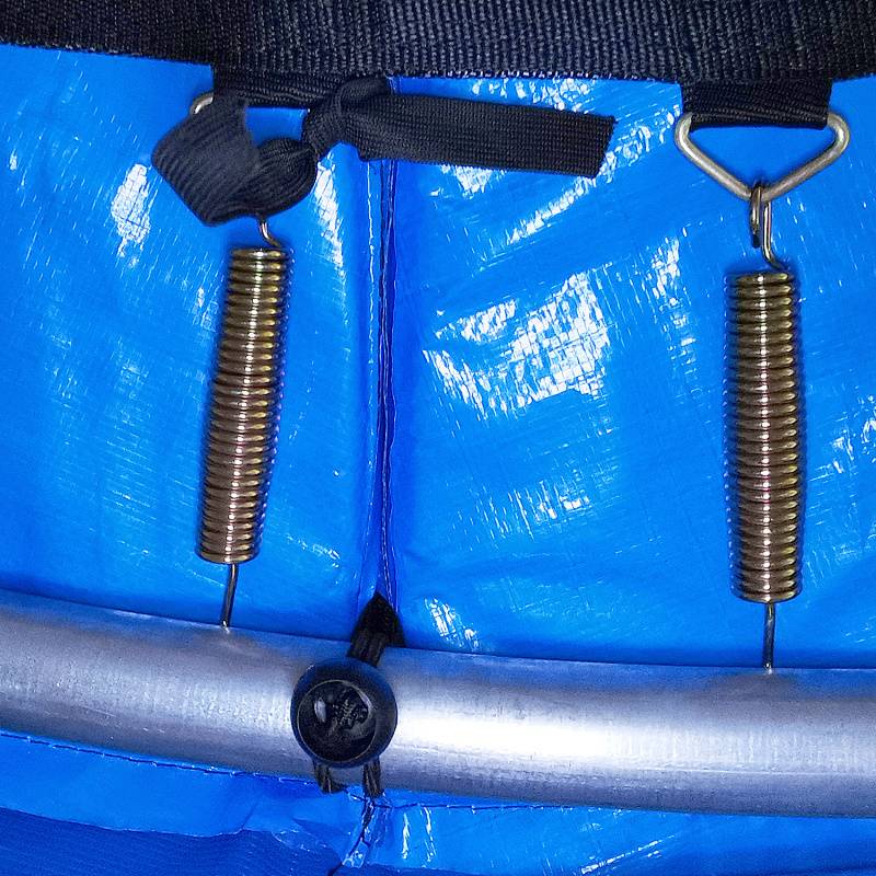 Zwei Metallfedern, die mit schwarzen Riemen an einer blauen Oberfläche befestigt sind, mit einem silbernen Stab unten, möglicherweise Teil einer Trampolinanlage.