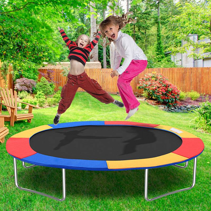 Kinder springen freudig auf einem bunten Trampolin in einer Hinterhofartenumgebung, umgeben von Grün und Holzmöbeln.
