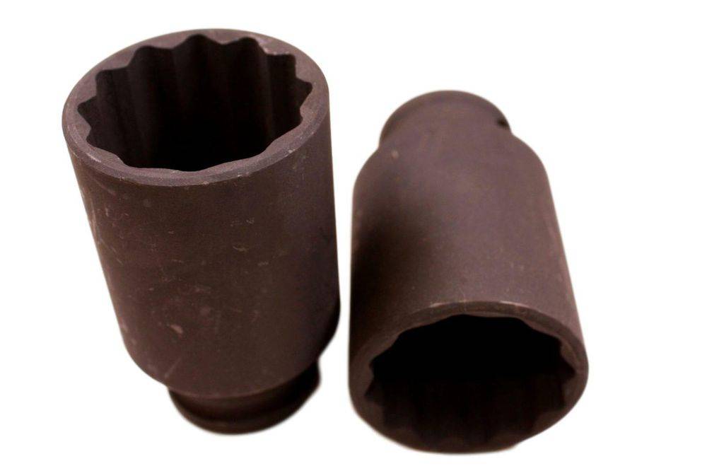 Zwei Metallhülsen mit hohler zylindrischer Form und gekerbtem Innenraum, die zum Aufstecken auf Muttern oder Schraubenbolzen bei mechanischen Arbeiten verwendet werden.